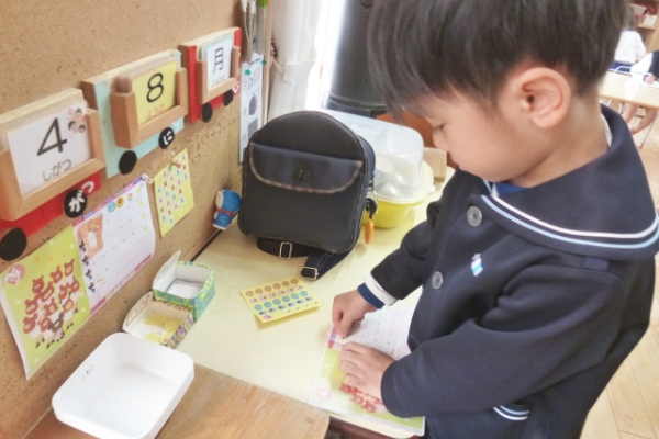 連絡帳にシールを貼っている子ども